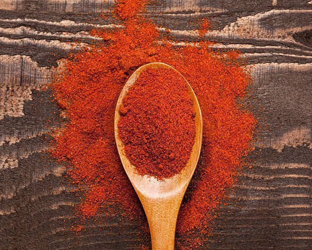 Close up of ground paprika in wooden spoon 