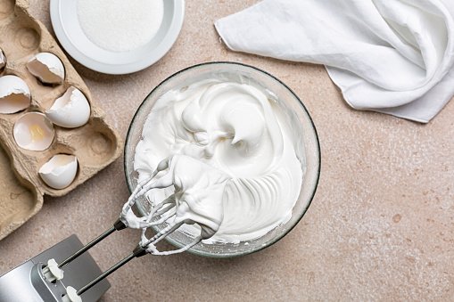 Beaten egg whites with sugar  for Meringue in a mixing bowl with an electric hand whisk. 